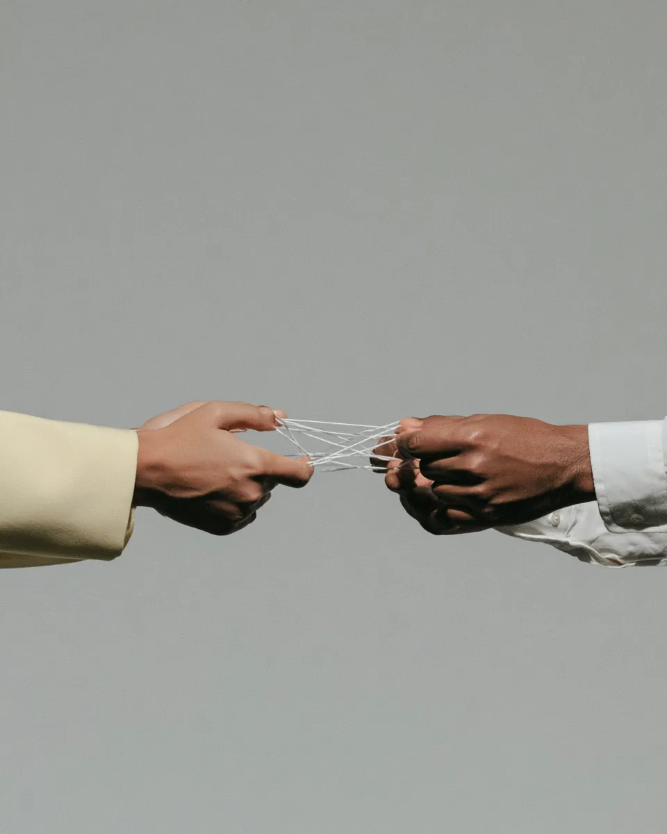 Four hands holding a string figure together
